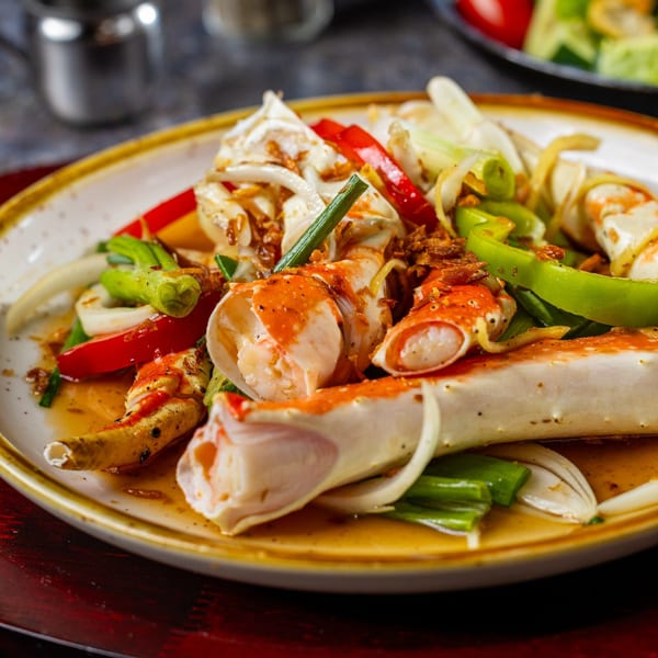 The Roasted Crab's king crab legs with bell peppers, onions, and sauce on a plate.