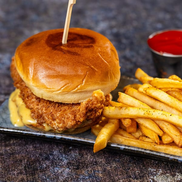 Crispy fried seafood sandwich with melted cheese and a side of golden french fries and ketchup.